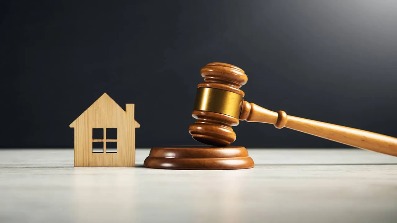 A gavel and a house on a table, symbolizing the legal aspects of rental deposit guarantees.